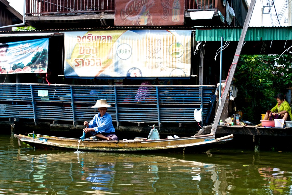 A man cooking next to the restaurant inside of the floating market.